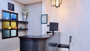 A reception desk with a computer monitor, a clock, and a framed quote on the wall. - P'Ja House by Lorenzo Property (Hat Yai)