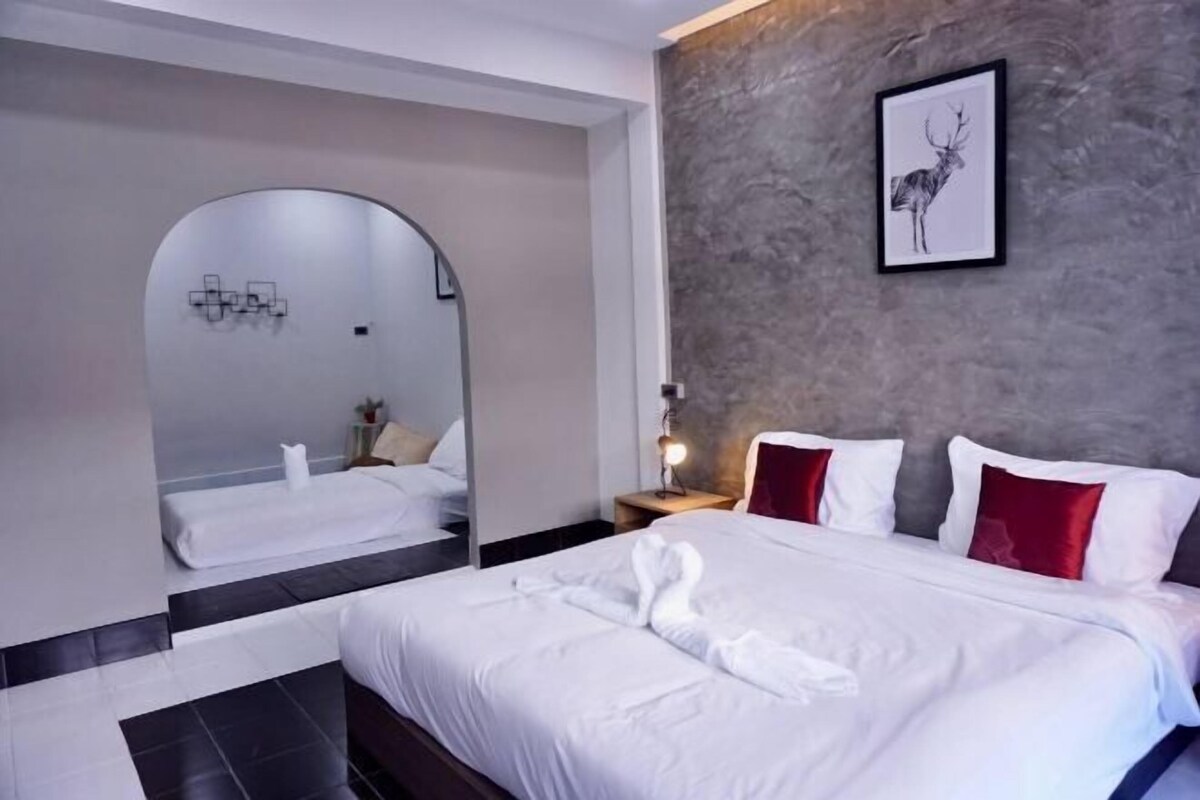 Una habitación de hotel moderna con una cama grande, un espejo, un cuadro enmarcado y una mesita de noche.
