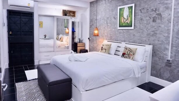A modern bedroom with a large bed, bedside tables, a wardrobe, and a gray textured wall. - P'Ja House by Lorenzo Property (Hat Yai)