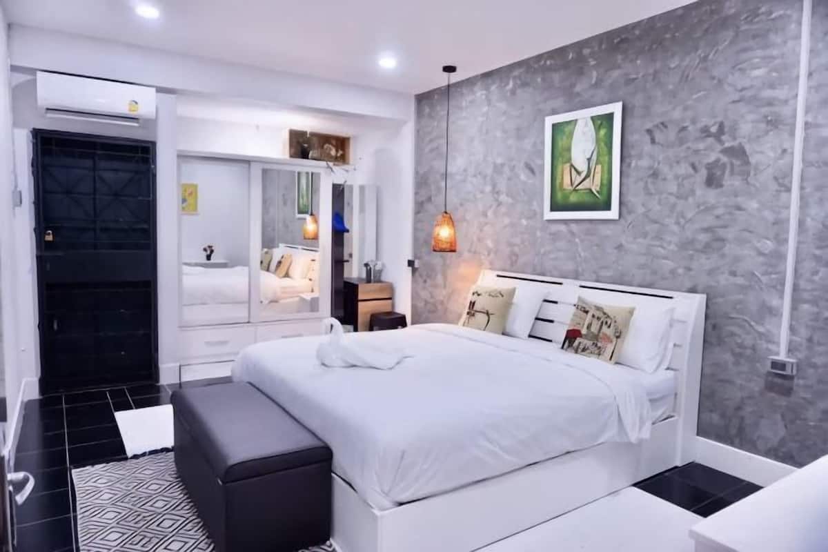 Ein modernes Schlafzimmer mit einem großen Bett, Nachttischen, einem Kleiderschrank und einer grauen, strukturierten Wand.