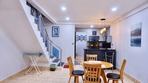 A dining area with a round table and chairs, a staircase, and a kitchen in the background. - P'Ja House by Lorenzo Property (Hat Yai)
