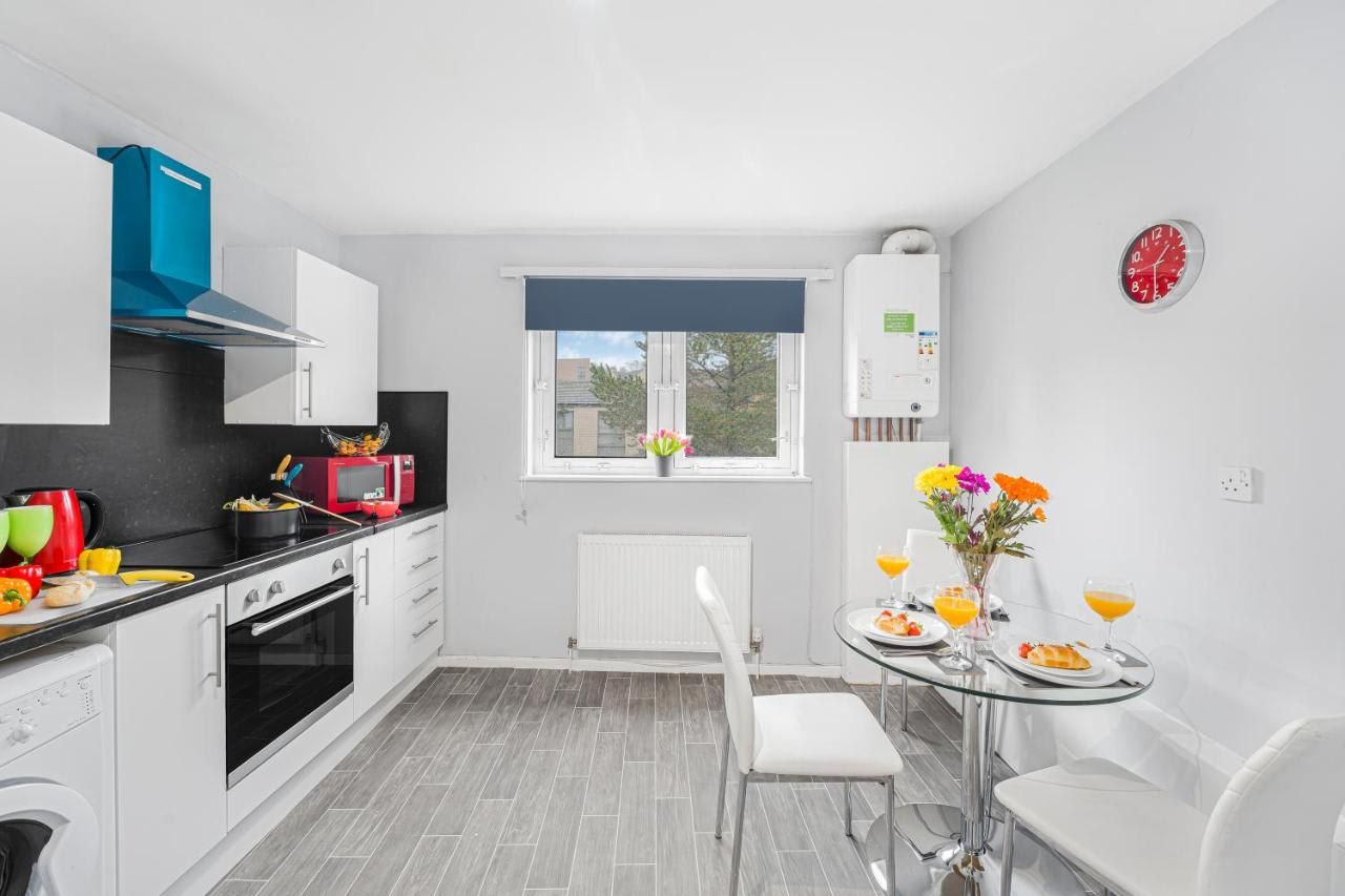 A modern kitchen with white cabinetry, a black countertop, a red microwave, and a blue range hood.