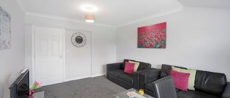 A modern living room with a sofa, coffee table, and a painting on the wall.