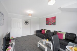 A modern living room with a sofa, coffee table, and a painting on the wall.