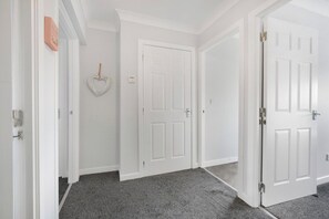 A hallway with white doors, a heart-shaped decoration, and a textured floor.