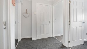 A hallway with white doors, a heart-shaped decoration, and a carpeted floor.