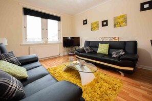 A living room with a sofa, a coffee table, and a television. - Premier - Chapel House with Driveway! (Cleland)