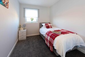 Une chambre à coucher avec un lit, une table de chevet, une fenêtre donnant sur un beau paysage et une petite commode.