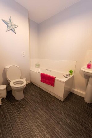 A bathroom with a toilet, a bathtub, and a sink.
