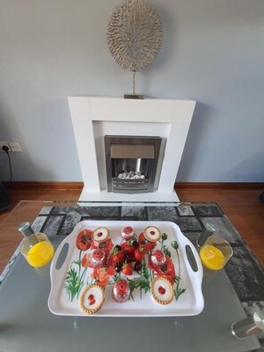 Une table à manger avec une assiette blanche remplie de nourriture et deux verres de jus d’orange.