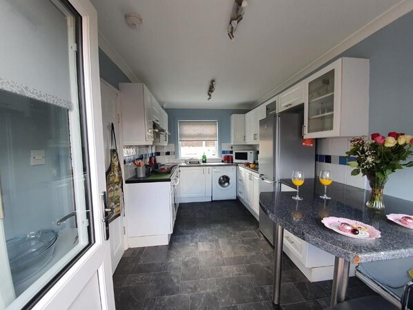 A modern kitchen with white cabinets, a built-in oven, and a dining area with a table set for two.