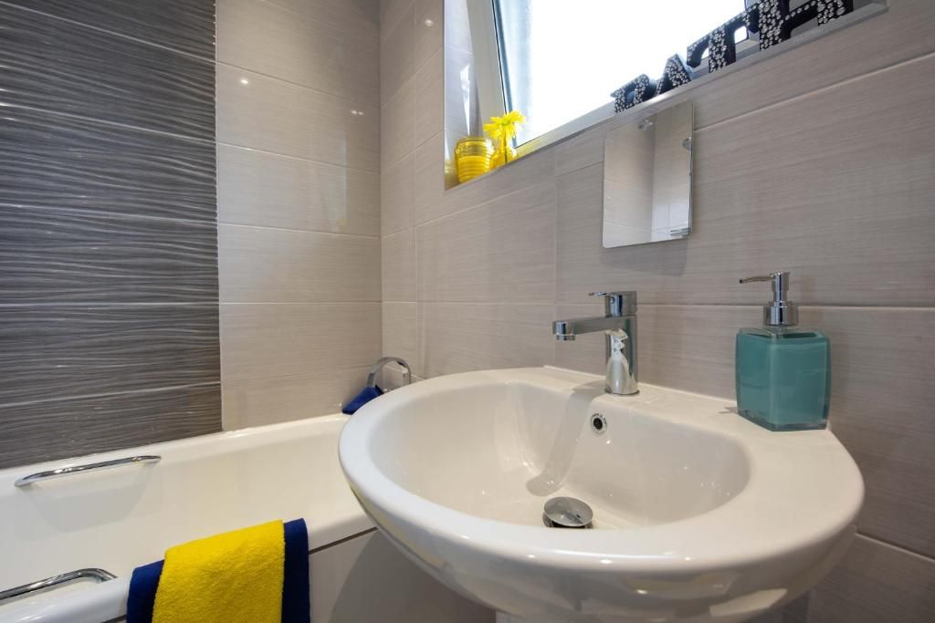 A bathroom with a white sink, a mirror, and a bathtub.