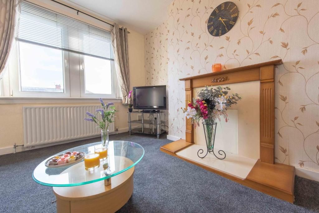 Ein Hotelzimmer mit einem Glastisch, einem Kamin, einem Fernseher und einem fenster mit Vorhängen.
