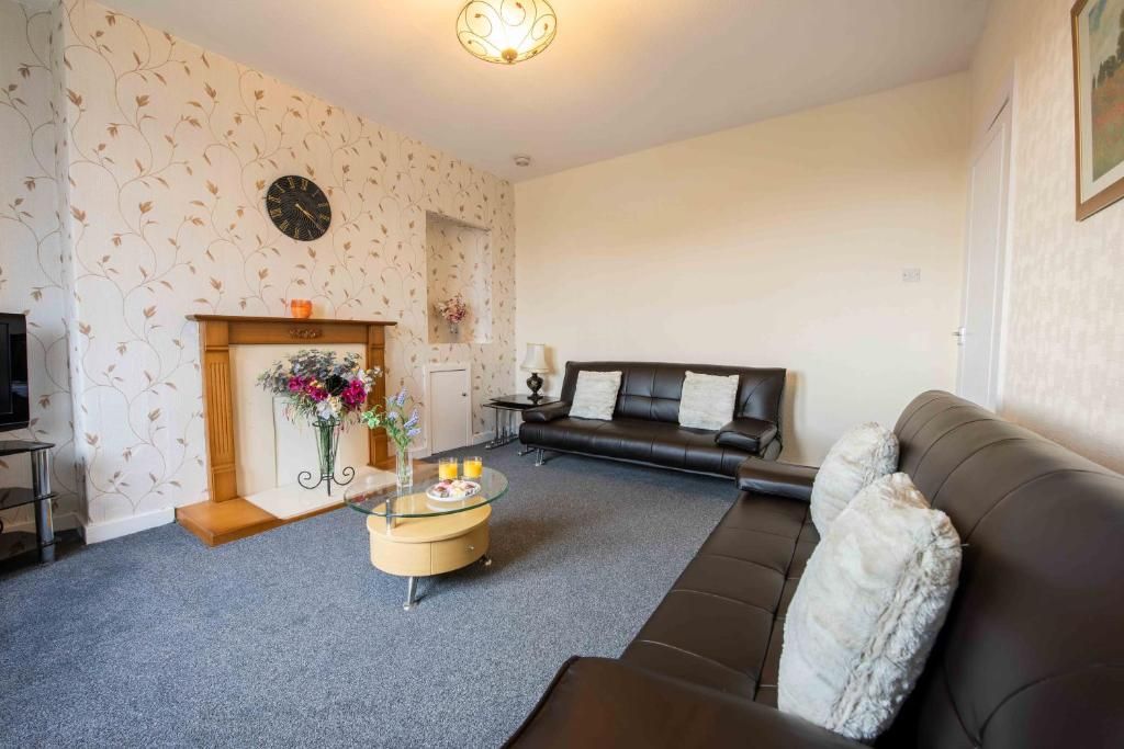 Un salon avec une cheminée, un canapé, une table basse et une horloge au mur.