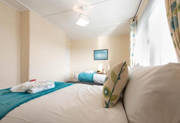 Habitación de hotel con cama, mesita de noche, lámpara y ventana con cortinas.