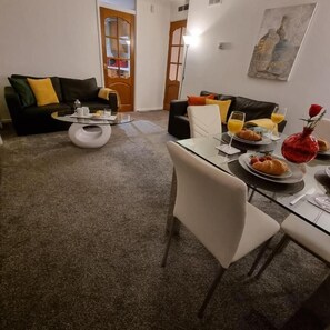 A dining area with a glass table, chairs, and a breakfast setting including croissants and orange juice.