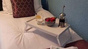 A neatly made bed with a tray of breakfast items including a bowl of strawberries, a glass of milk, and a coffee maker. - Premier - Whifflet Apartment (North Lanarkshire)