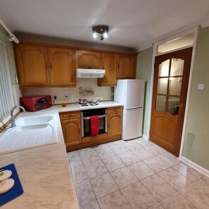 A kitchen with wooden cabinets, a white refrigerator, a microwave, and a sink.