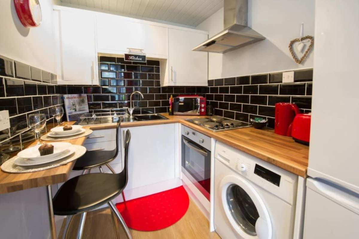 A compact kitchen with a washing machine, a microwave, and a sink.