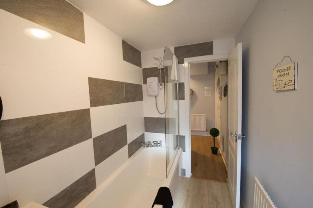 Un baño moderno con ducha, toallero y un cartel que indica el acceso a los servicios.