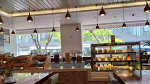 Een modern café met houten meubels, hanglampen en een vitrine met gebak.