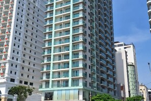 A high-rise building with multiple floors, balconies, and a clear sky. - Aparthotel in A La Carte - 2 bedrooms, balcony, beachfront, rooftop pool, central (Da Nang)