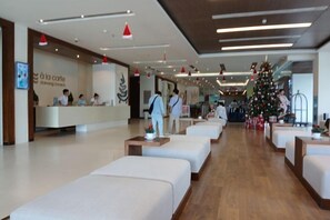 A hotel lobby with a reception desk, seating area, and a Christmas tree. - Aparthotel in A La Carte - 2 bedrooms, balcony, beachfront, rooftop pool, central (Da Nang)