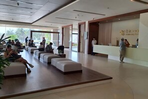 A hotel lobby with seating areas, a reception desk, and a large window providing a view. - Aparthotel in A La Carte - 2 bedrooms, balcony, beachfront, rooftop pool, central (Da Nang)