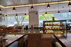 A modern cafe interior with a central counter, seating area, and a display case of pastries. - Aparthotel in A La Carte - 2 bedrooms, balcony, beachfront, rooftop pool, central (Da Nang)
