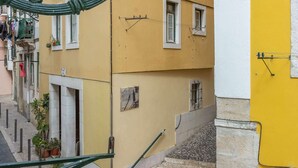 A yellow building with a staircase, a metal railing, and a street lamp. - Suprema loft l (Lisboa)