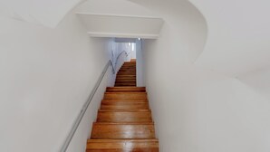 A staircase with wooden steps leading upwards, surrounded by white walls and a curved archway. - Suprema loft l (Lisboa)
