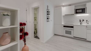 A modern kitchen with white cabinetry, a microwave, and a wine rack. - Suprema loft l (Lisboa)