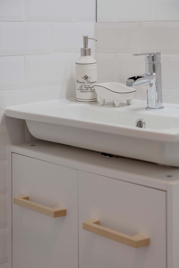 A bathroom with a white sink, a soap dispenser, and a small decorative pig.