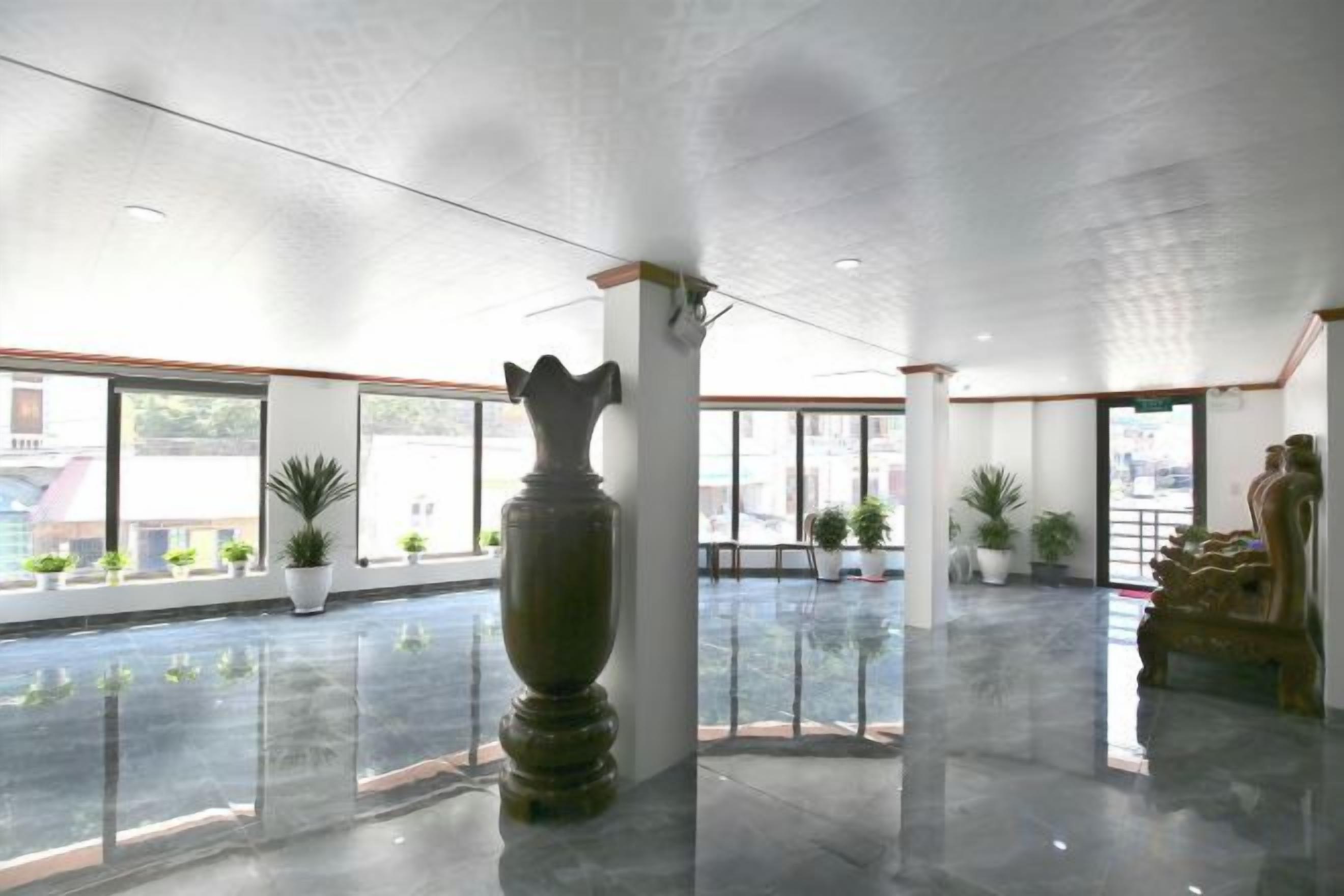 A spacious lobby with a large vase, potted plants, and a statue.