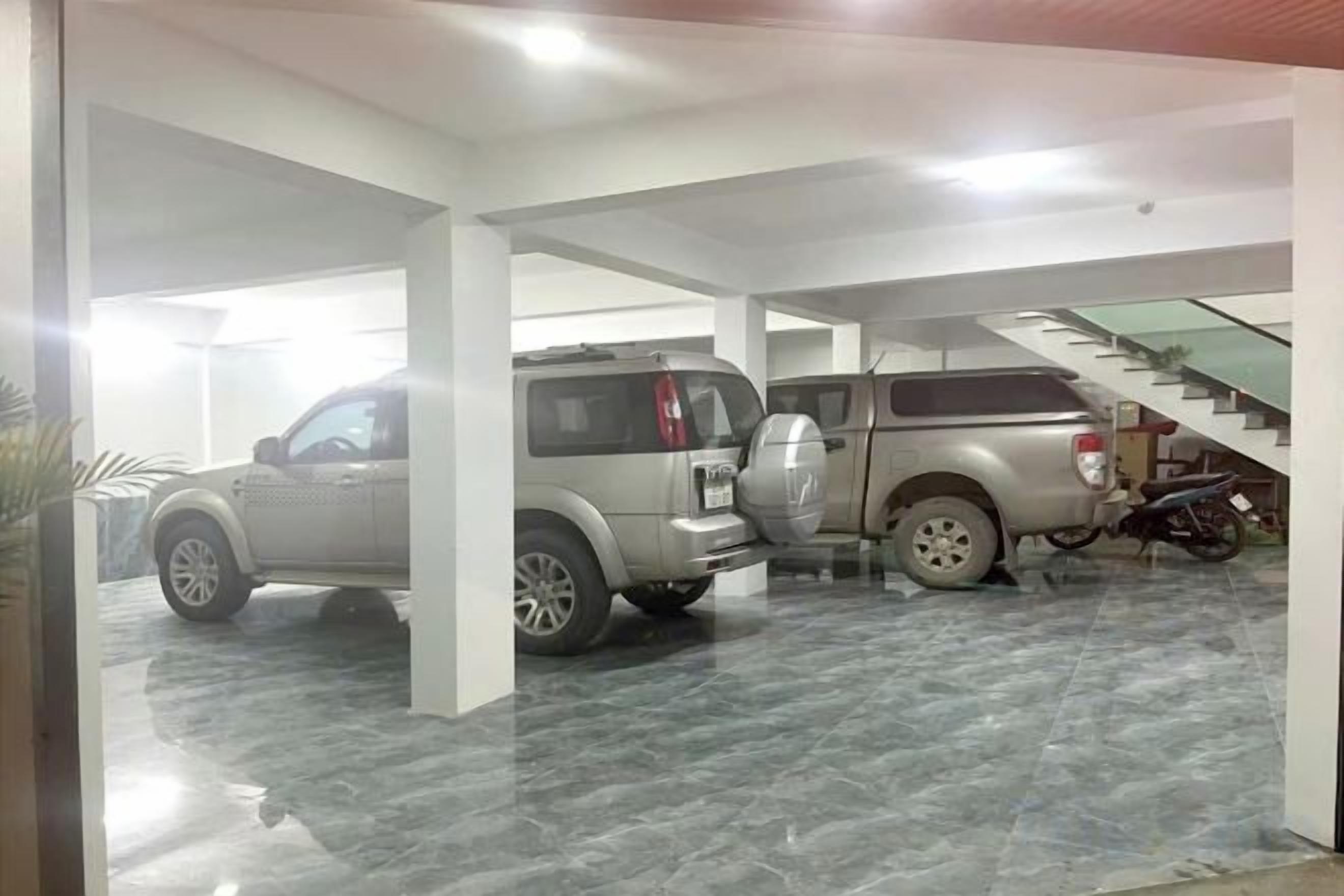 A parking garage with two SUVs and a motorcycle, featuring a staircase and a tiled floor.
