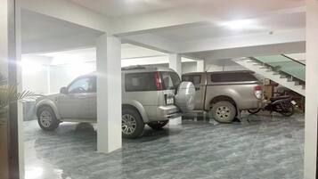 A parking garage with two SUVs and a motorcycle, featuring a staircase and a tiled floor.
