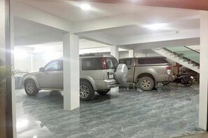 A parking garage with two SUVs and a motorcycle, featuring a staircase and a tiled floor. - Tien Dat Hotel (TT. Meo Vac)