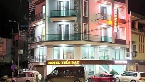 En byggnad med flera våningar, och en skylt som visar texten ”HOTEL TIÊN DAT”. Flera bilar är parkerade framför byggnaden, och den har balkonger på de övre våningarna.