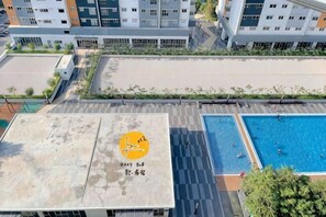 Une terrasse sur le toit avec une piscine, une vue sur un quartier résidentiel et un bâtiment orné d’un logo.