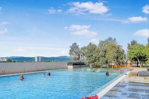 A swimming pool with clear blue water, surrounded by trees and a view of distant mountains. - KLIA transit hub@ Kota Warisan (Sepang)
