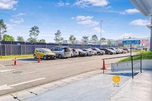 Een parkeerplaats met meerdere auto's, een blauw bord en een omheind gebied.