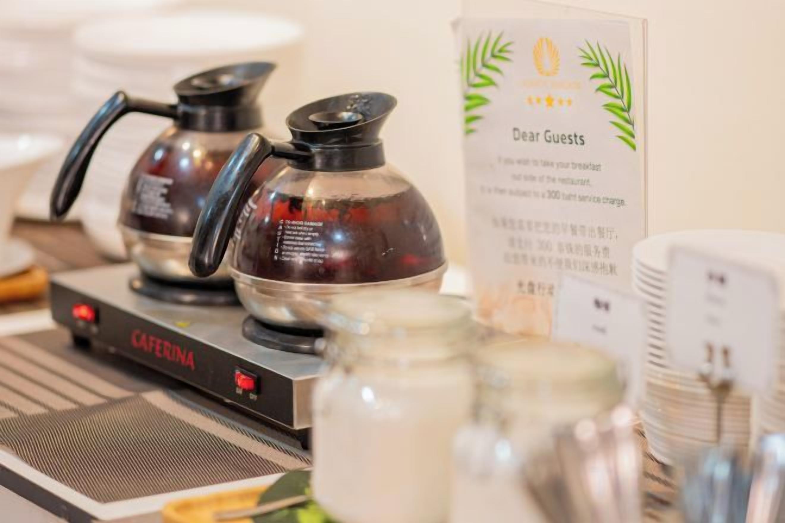 A coffee station with two coffee makers and a sign for guests.
