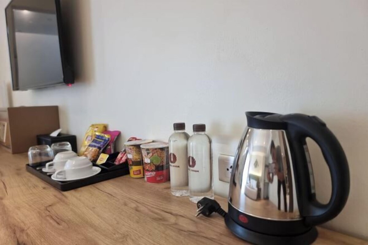 Un coin cuisine équipé d’une bouilloire, de tasses et de divers aliments disposés sur un plateau.