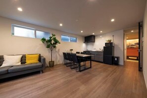 A modern living space with a sofa, dining table, chairs, and a kitchen area. - EI･GESSHO (Osaka)