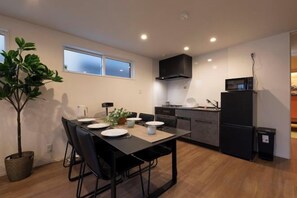 A modern kitchen with a dining table, chairs, and a microwave. - EI･GESSHO (Osaka)