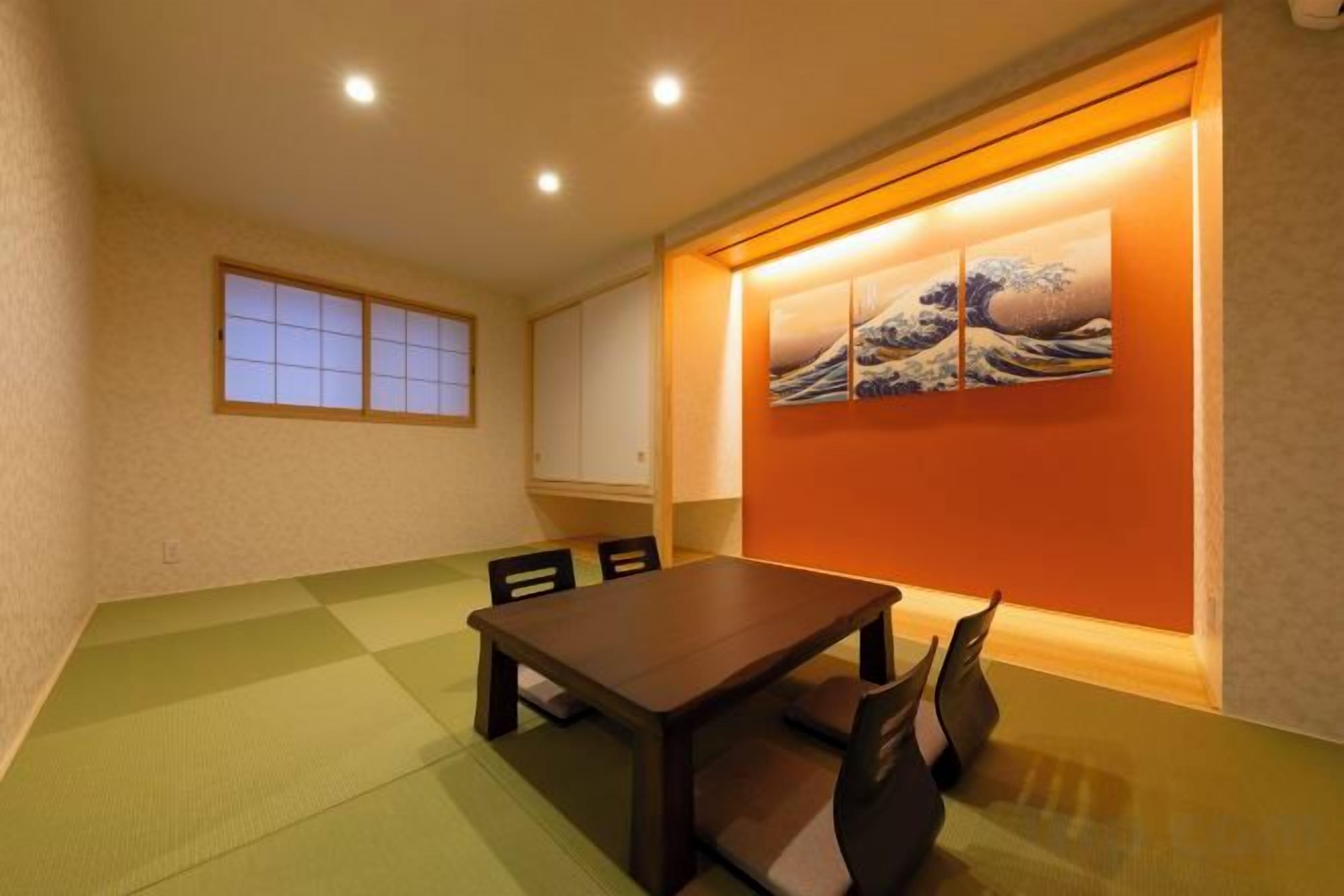 A room with a dining table, chairs, a window, and artwork on the wall.