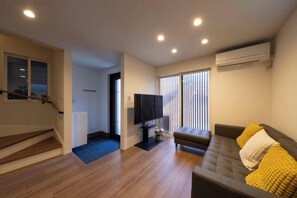 A living room with a sofa, a flat-screen TV, and a staircase. - EI･GESSHO (Osaka)