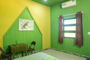 Una stanza con una parete verde, una finestra con tende, una mappa appesa al muro e una scrivania con sedie.