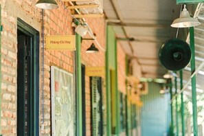 A corridor with brick walls, hanging lights, and a sign reading 'Phong Chieu Hoi'. - The snail haven pub and stay (Con Dao Island)