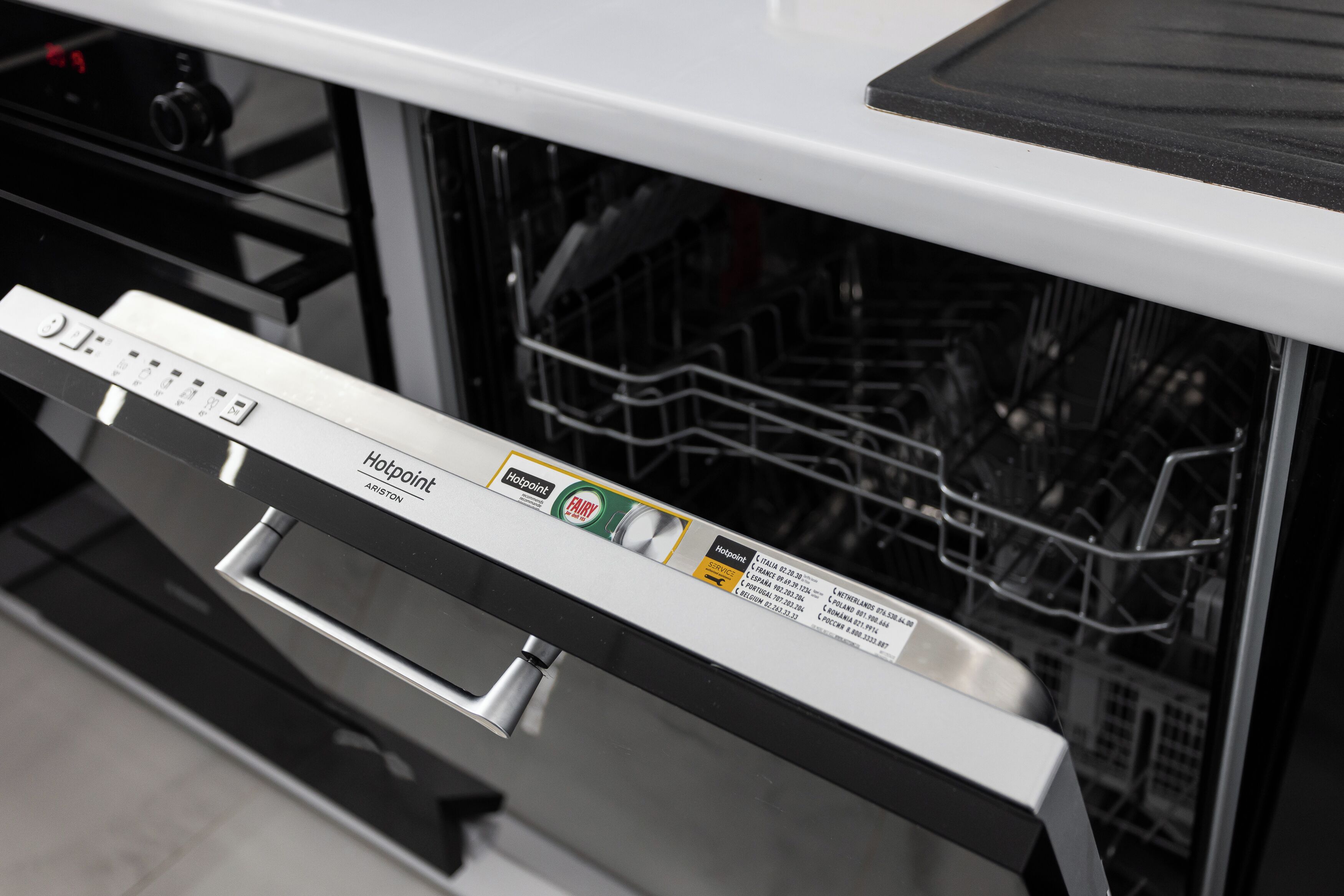 A dishwasher with a control panel and a label indicating it is a Hotpoint brand.
